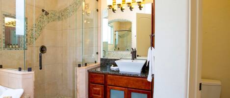Un baño con ducha envuelta en cristal, lavabo con tocador y un inodoro.
