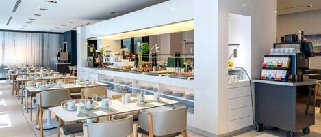 A modern dining area with tables and chairs, a buffet counter, and a coffee station.
