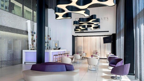A modern interior with a reception desk, seating area, and a bar.