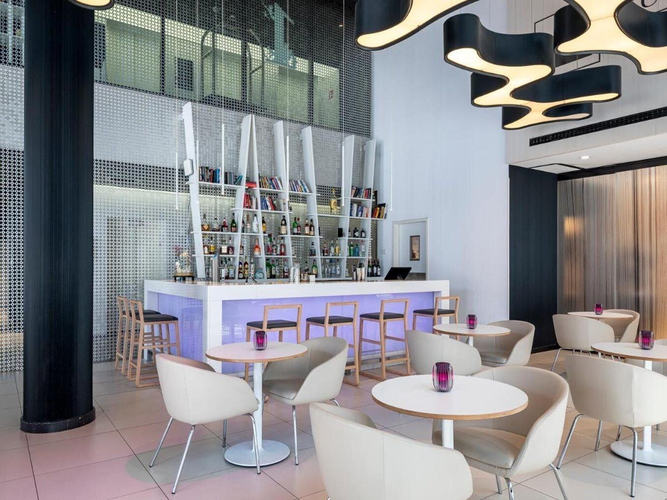 Un espace bar moderne doté d’un comptoir central, de bibliothèques et de sièges.