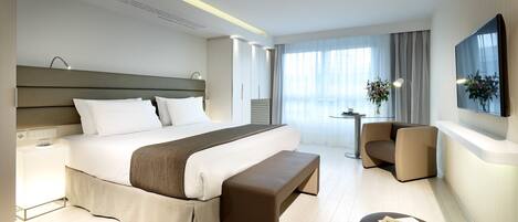 Une chambre d’hôtel moderne dotée d’un grand lit, d’un bureau et d’un coin salon confortable.