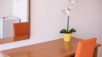 Una mesa de comedor de madera con una maceta amarilla que contiene una orquídea.