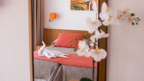 A neatly made bed with a red pillow, a white towel, and a wooden headboard. There is a painting on the wall and a vase with white flowers on the nightstand. - Hostal Los Pinos (Santa Eulalia del Rio)