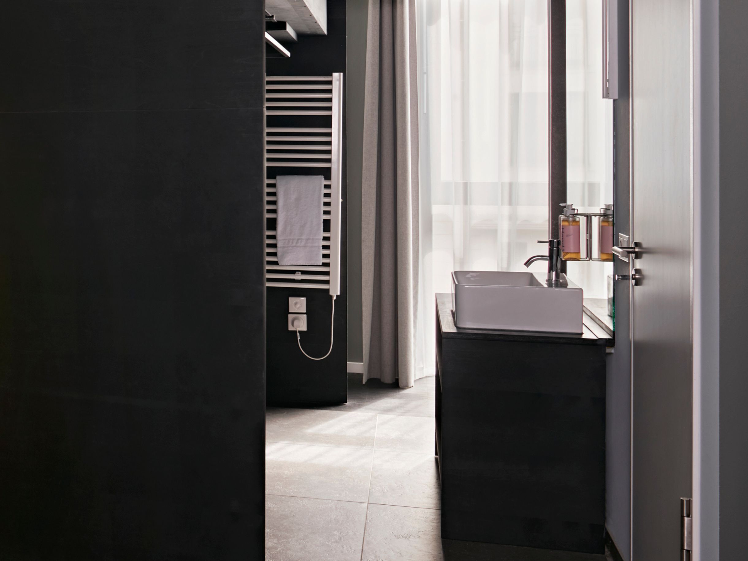 Een moderne badkamer met een donkere vloer, een wit wastafelmeubel en een spiegel.