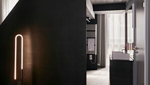 A modern bathroom with a dark floor, a white sink, and a towel rack. - Numa Berlin Boxer (Berlin)