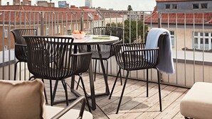 A balcony with a round table, four chairs, and a bowl of fruit. - Numa Berlin Boxer (Berlin)
