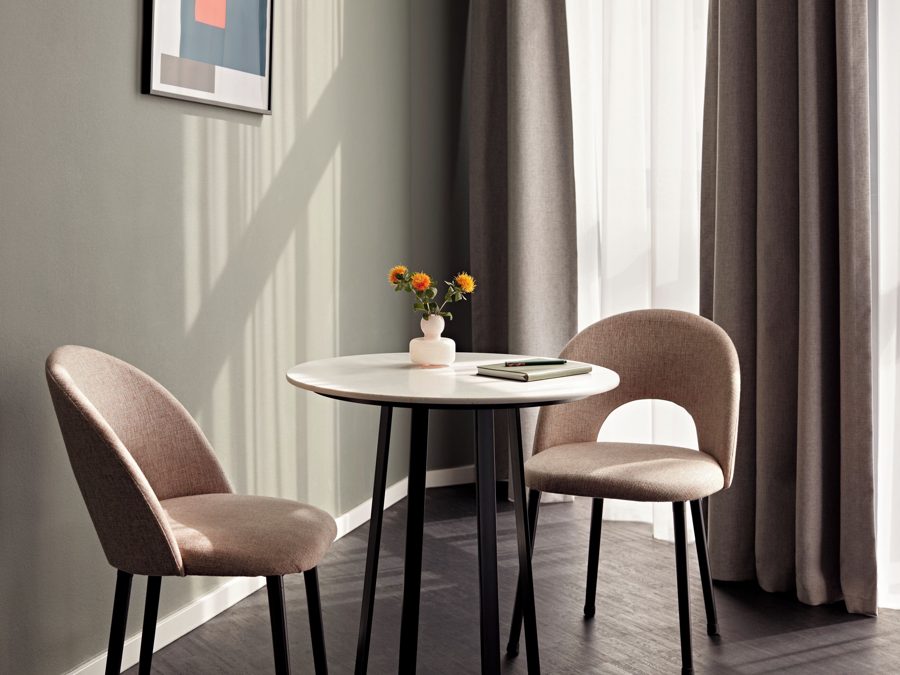 Ein modernes Zimmer mit zwei Stühlen, einem kleinen Tisch und einer Vase mit Blumen.