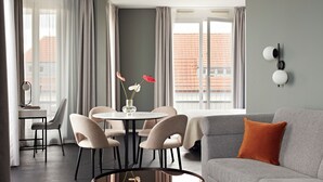 A modern living room with a grey sofa, a round coffee table, and a dining area with a round table and four chairs. - Numa Berlin Boxer (Berlin)