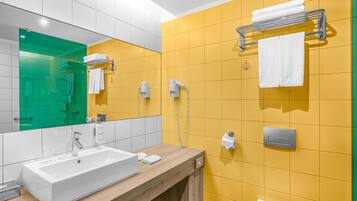 Un bany modern amb un lavabo blanc, rajoles grogues, un mirall i una barra de tovalloles.