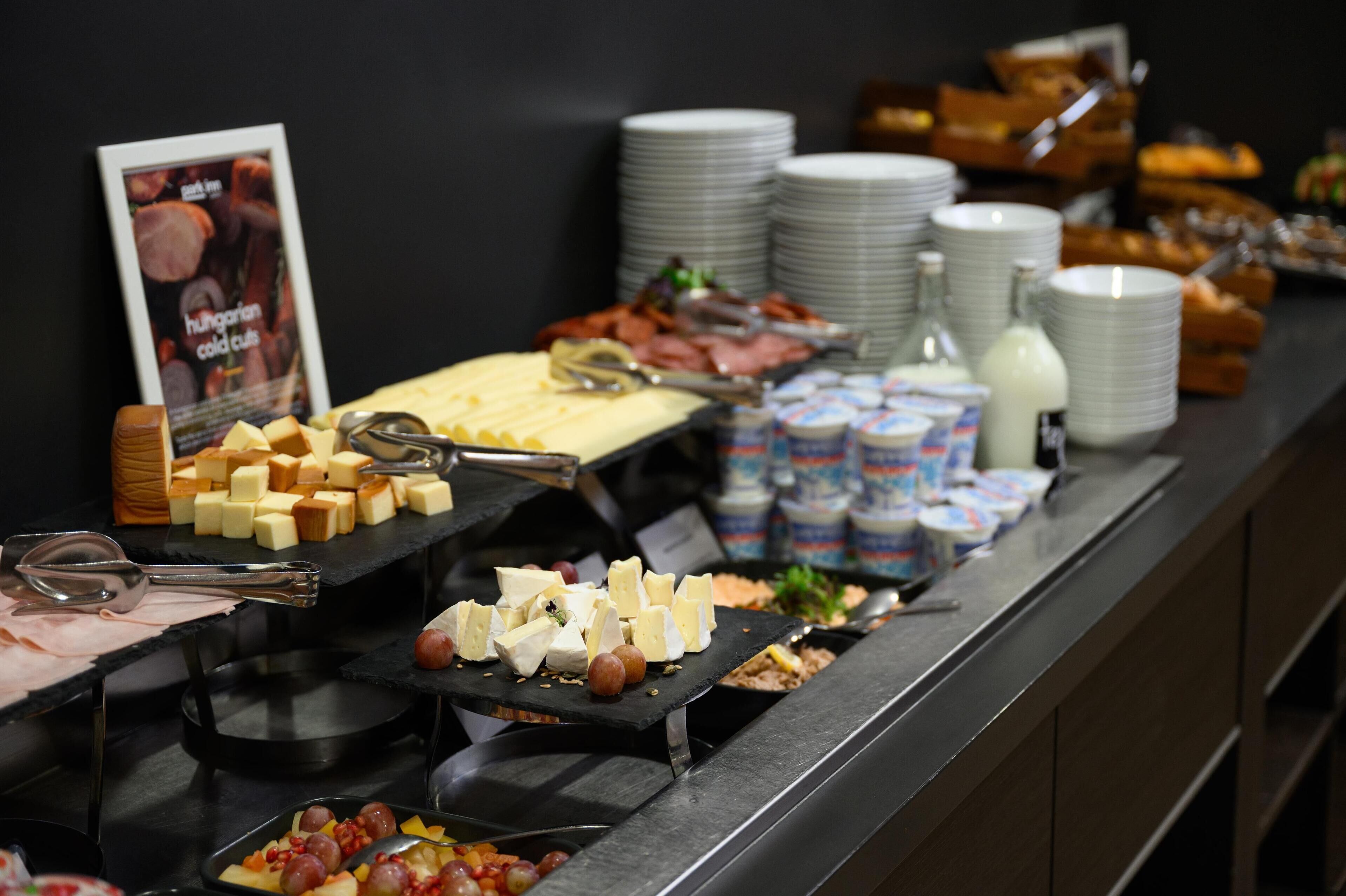 A buffet with various cheeses, meats, and condiments.