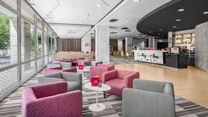 Un hall d’hôtel moderne, doté d’espaces de détente, d’un bar et d’un comptoir d’accueil.