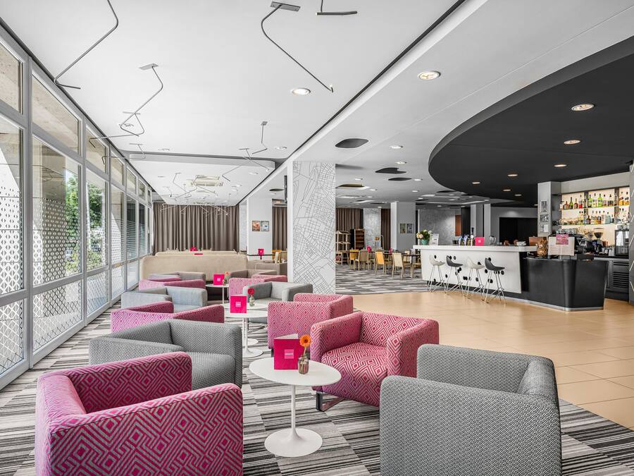 Un moderno vestíbulo de hotel con zonas de estar, un bar y una recepción.