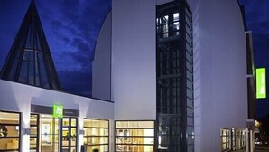 Un edificio moderno con una estructura de vidrio triangular y una fachada blanca curva.