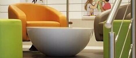 A modern interior with a large bowl-shaped table, a green armchair, and a staircase with a glass railing.
