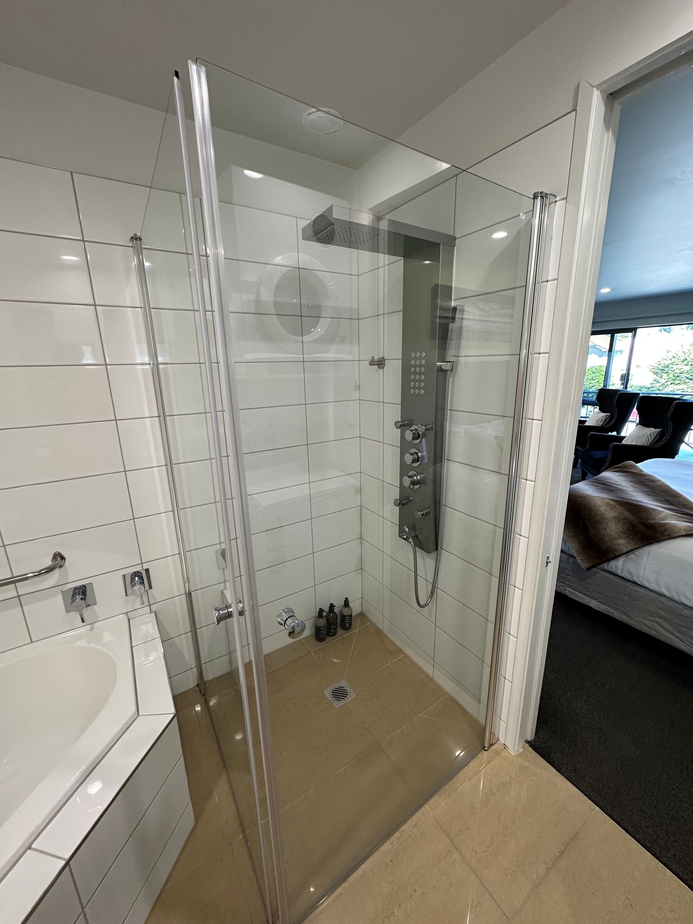 Un bagno moderno con cabina doccia in vetro, vasca da bagno separata e WC a vista.
