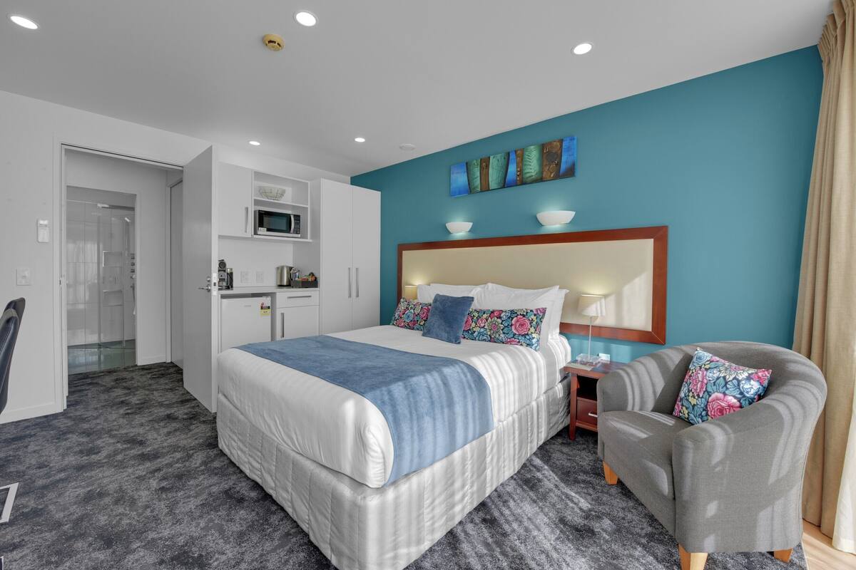 A hotel room with a large bed, a sofa, a desk, and a microwave.