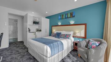 A hotel room with a large bed, a sofa, a desk, and a microwave.