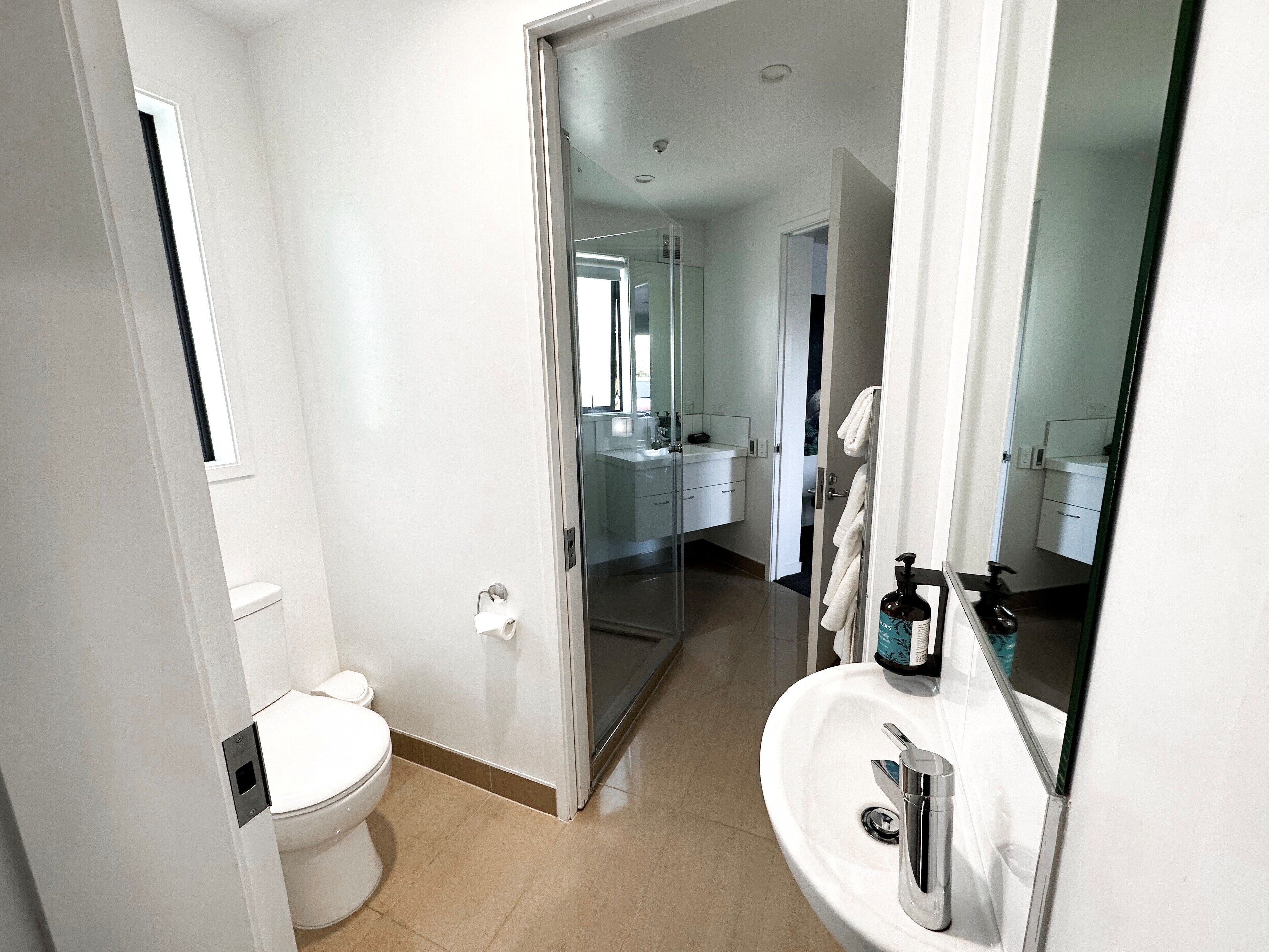 Un baño moderno con inodoro, lavamanos y cabina de ducha de vidrio.