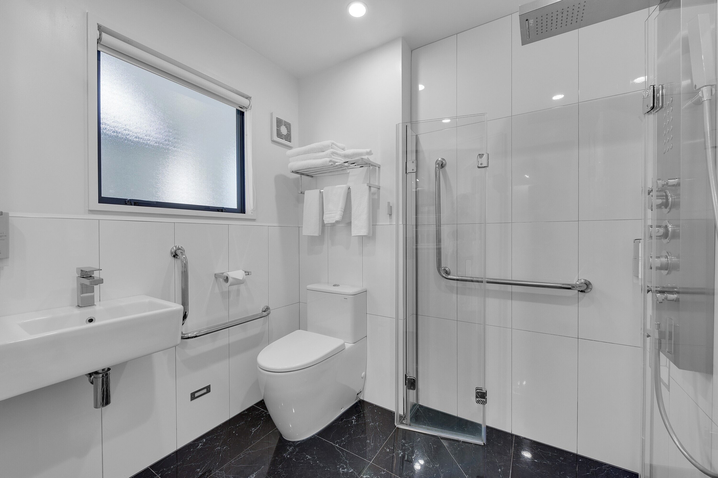 A modern bathroom with a toilet, sink, and glass shower enclosure.