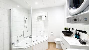 A modern bathroom with a glass-enclosed shower, a white toilet, and a built-in washing machine.