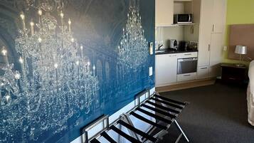 Habitación de hotel con una gran obra de arte azul, una cocina moderna y una cama con cabecero.