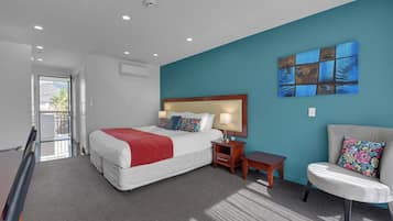 A modern hotel room with a large bed, a desk, a chair, and a view of the outdoors.