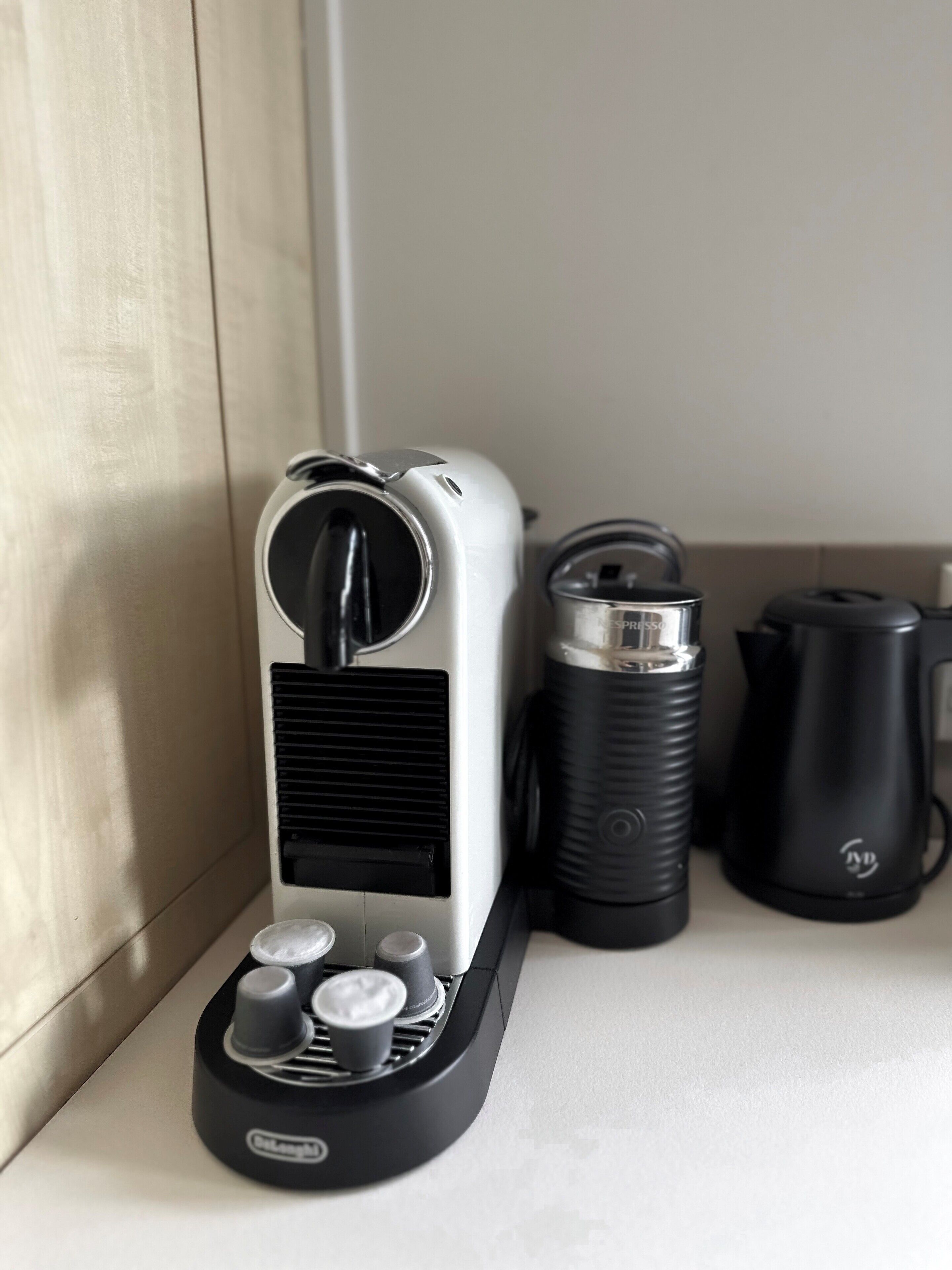 A coffee maker with a black and white design, a kettle, and a thermos on a kitchen counter.