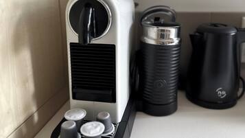 A coffee maker with a black and white design, a kettle, and a thermos on a kitchen counter.