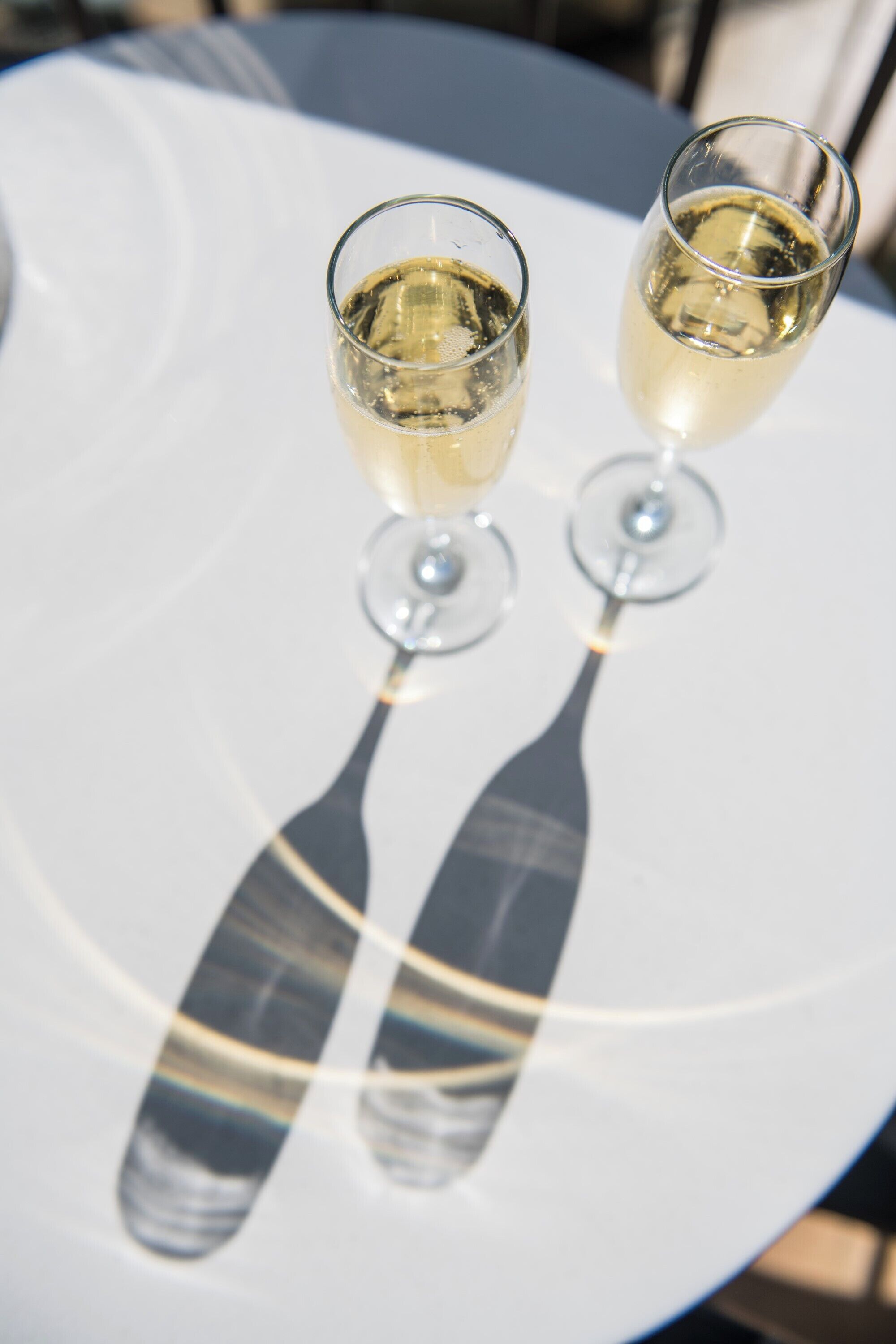 Deux verres de vin blanc sur une table blanche.