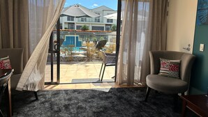 A room with a sliding glass door leading to a patio with a pool and outdoor furniture. - DeLorenzo's Studio Apartments (Nelson)