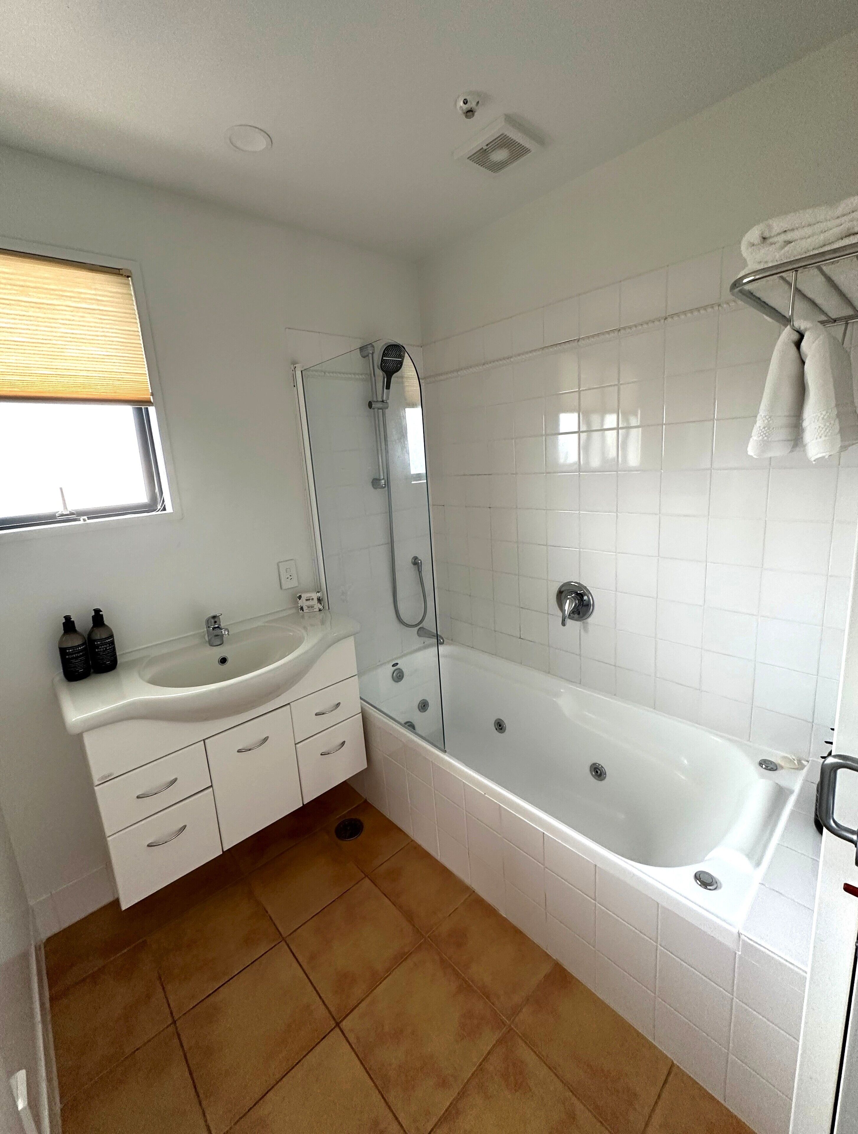 A bathroom with a white sink, vanity, and bathtub.