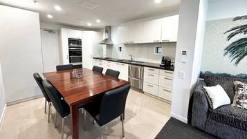 A modern kitchen with white cabinets, stainless steel appliances, and a dining area with a wooden table and chairs.
