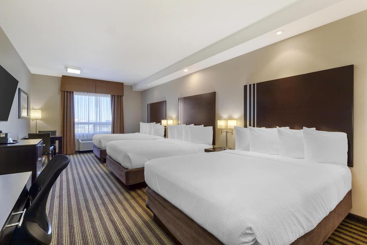 A hotel room with two beds, a desk, and a chair.