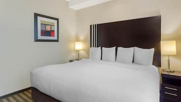 Habitación de hotel con una cama grande, dos mesitas de noche con lámparas, un cuadro en la pared y una alfombra a rayas.