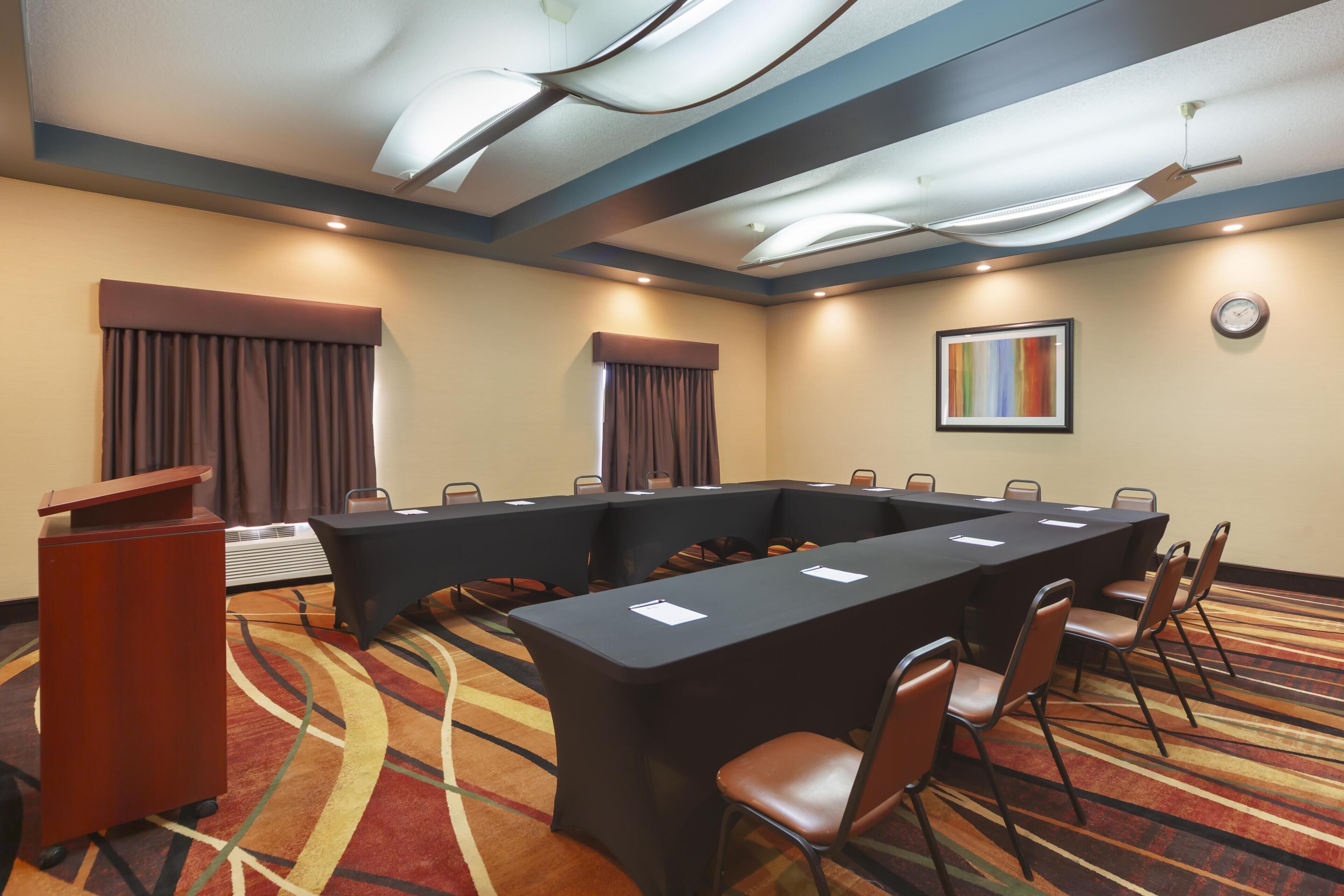 Un salón de conferencias con una larga mesa, sillas, un atril y un reloj en la pared.