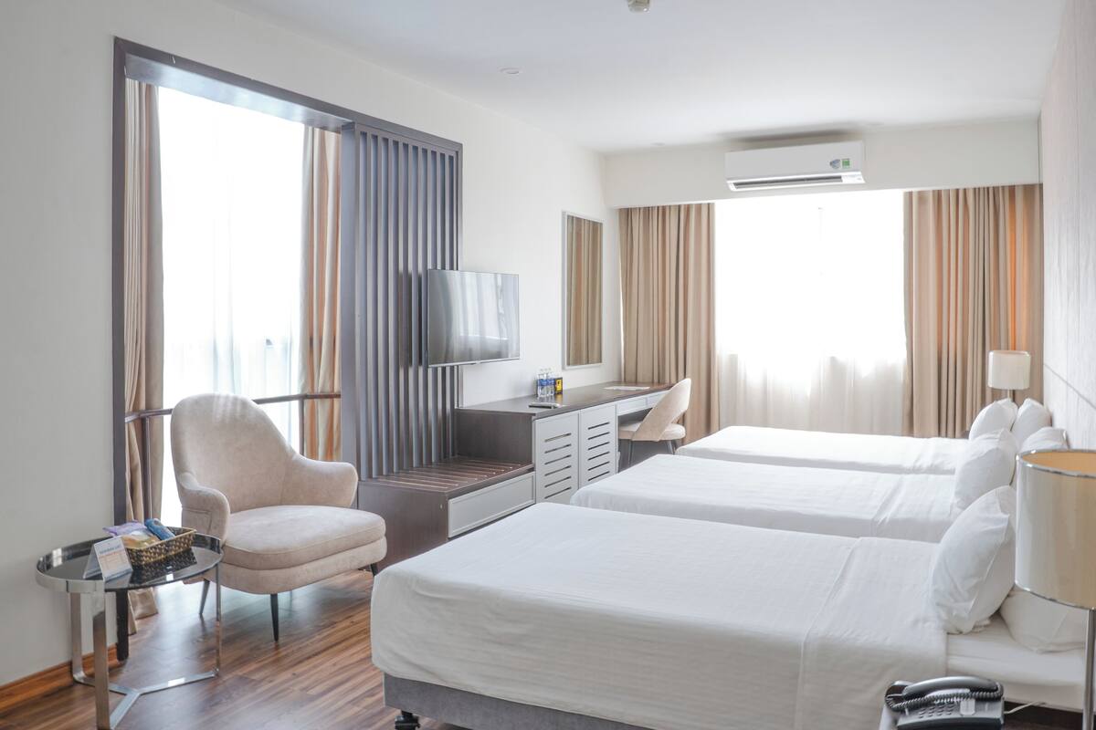 Une chambre d’hôtel avec deux lits, un bureau, une chaise et un téléviseur.