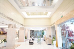 Un lobby espacioso con techo alto, asientos modernos y un amplio ventanal con vistas al exterior.