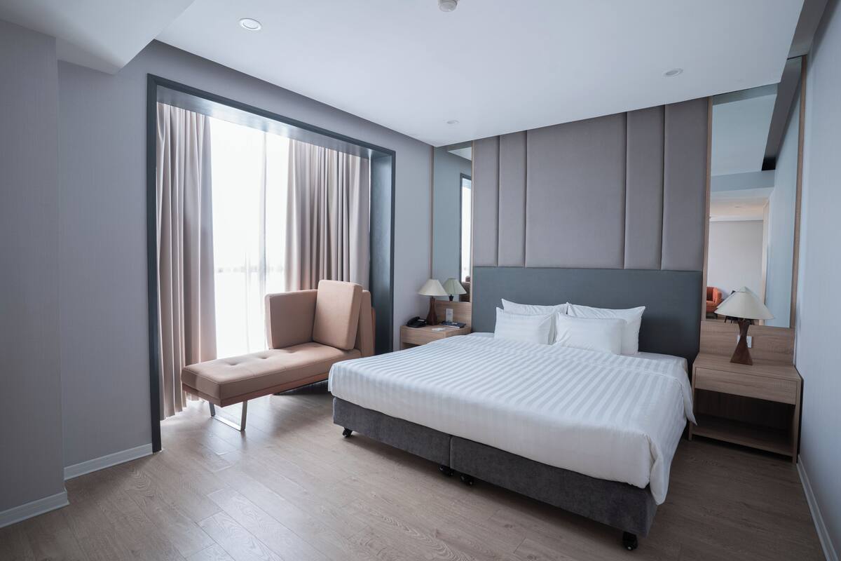 Une chambre d’hôtel moderne dotée d’un grand lit, d’un coin salon et d’une table de chevet avec une lampe.