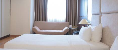 Habitación de hotel con una cama grande, un sofá, una lámpara y un equipo de aire acondicionado.