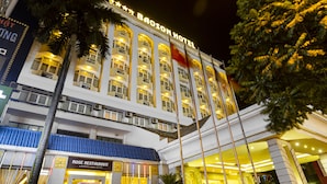 El Hotel Baoson, con su fachada iluminada, varios pisos y una bandera en la cima.