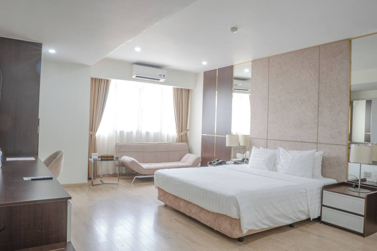 Une chambre d’hôtel moderne, dotée d’un grand lit, de tables de chevet, d’un bureau et d’une chaise.