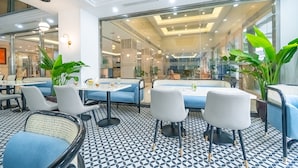 Un espacio interior moderno con mesas, sillas, ventanas amplias y plantas en macetas.