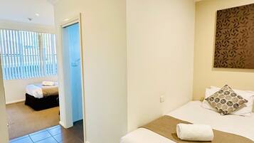 A hotel room with a bed, a small seating area, and a view through a door.