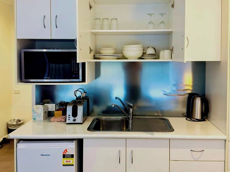 Una kitchenette compacta con microondas, lavabo y alacenas.
