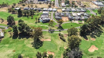 An aerial view of a residential area with houses, roads, and green spaces.