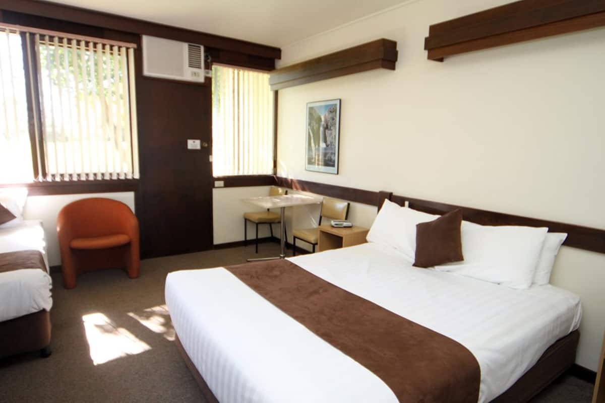 A hotel room with a large bed, a desk, and a chair.