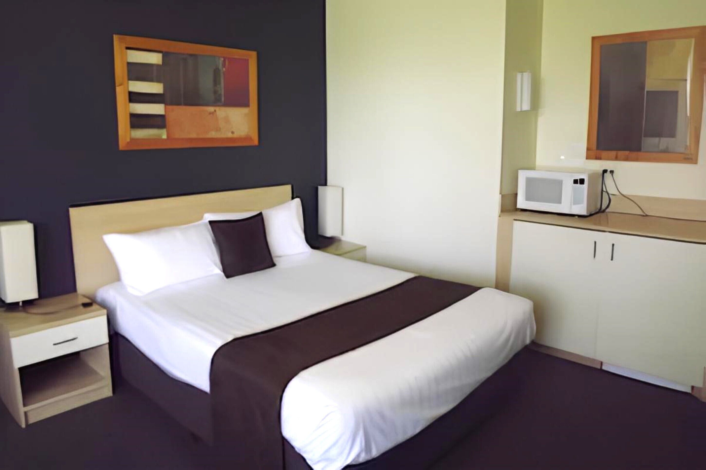 Een hotelkamer met een groot bed, een nachtkastje, een kledingkast en een magnetron.