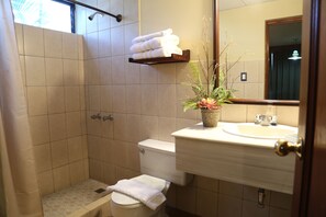 Een badkamer met douche, toilet, wastafel en een potplant.