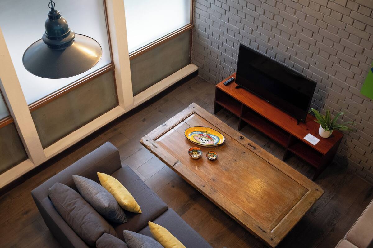 Ein modernes Wohnzimmer mit einer Couch, Couchtisch, Fernseher und einer Ziegelwand.