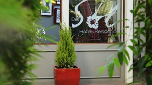Ein Hotel Eingang mit einem großen Fenster, das das Logo und den Namen 'Del Hotel & Residencia' zeigt.